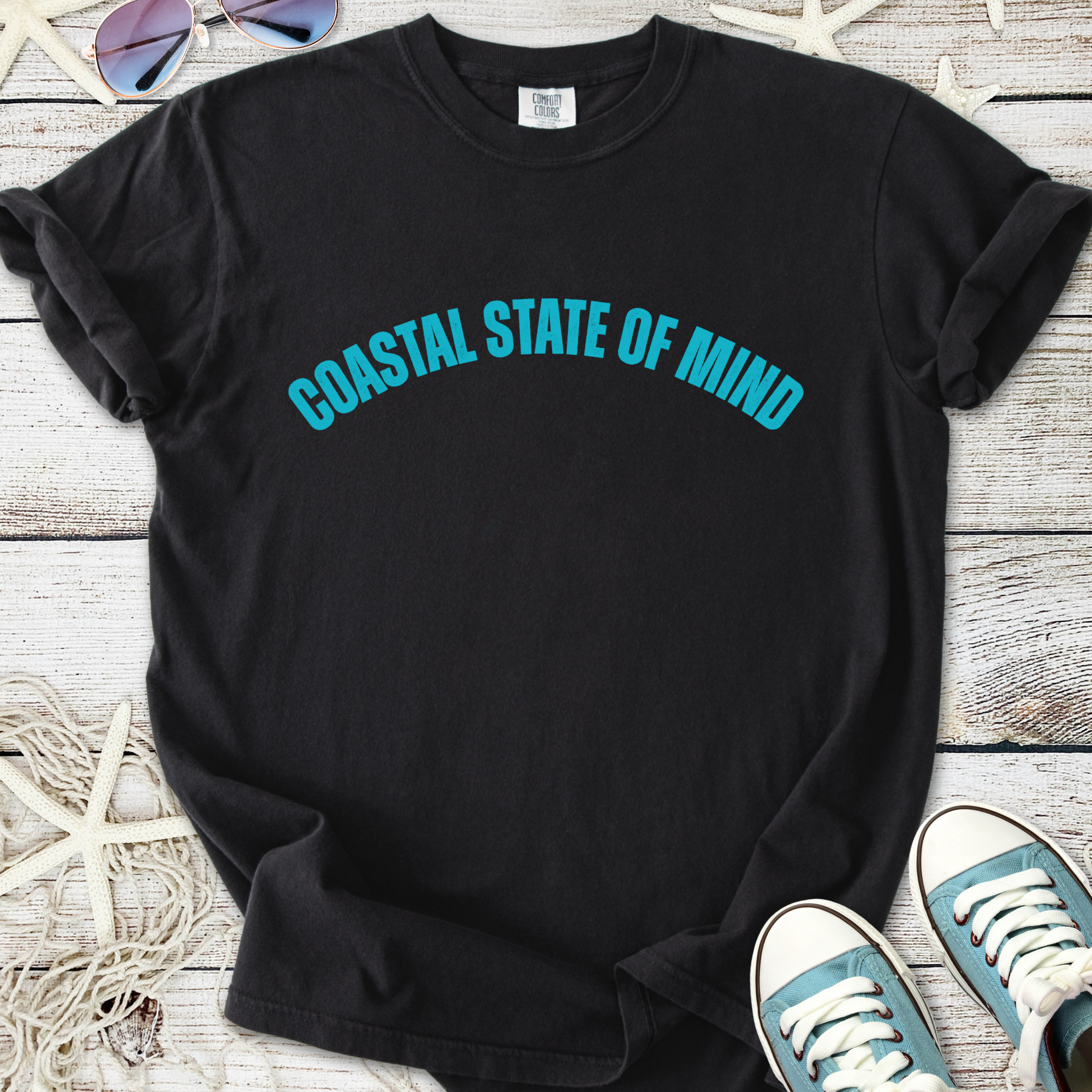 Black t-shirt featuring 'Coastal State of Mind' in turquoise, soft cotton material, perfect for casual wear.