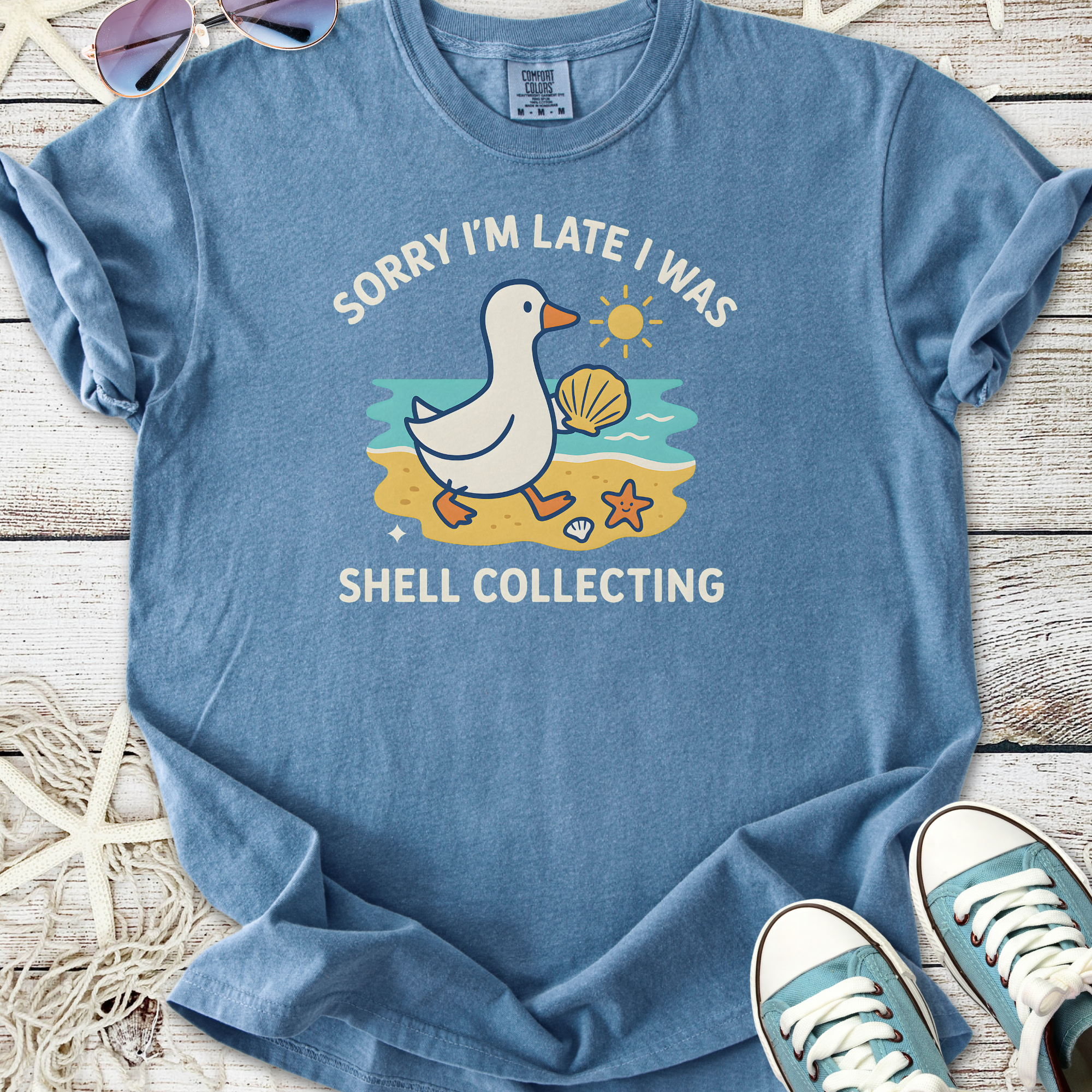 Blue graphic tee featuring a duck with the text 'Sorry I'm Late I Was Shell Collecting', perfect for casual wear.