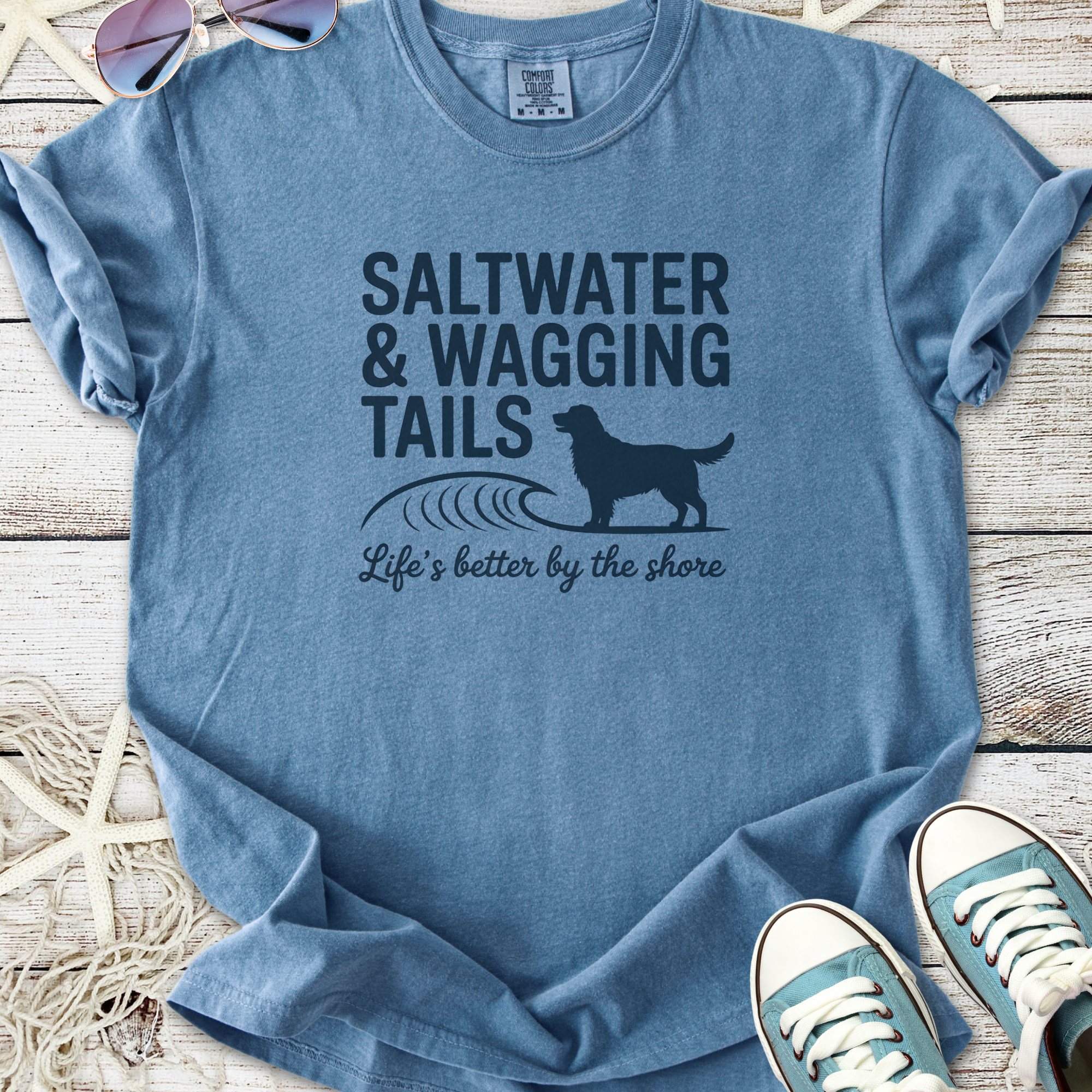 Blue graphic t-shirt featuring 'Saltwater & Wagging Tails' design, perfect for beach lovers and dog owners.