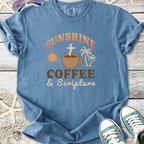 Blue graphic t-shirt featuring 'Sunshine Coffee & Scripture' design with sun and palm trees.