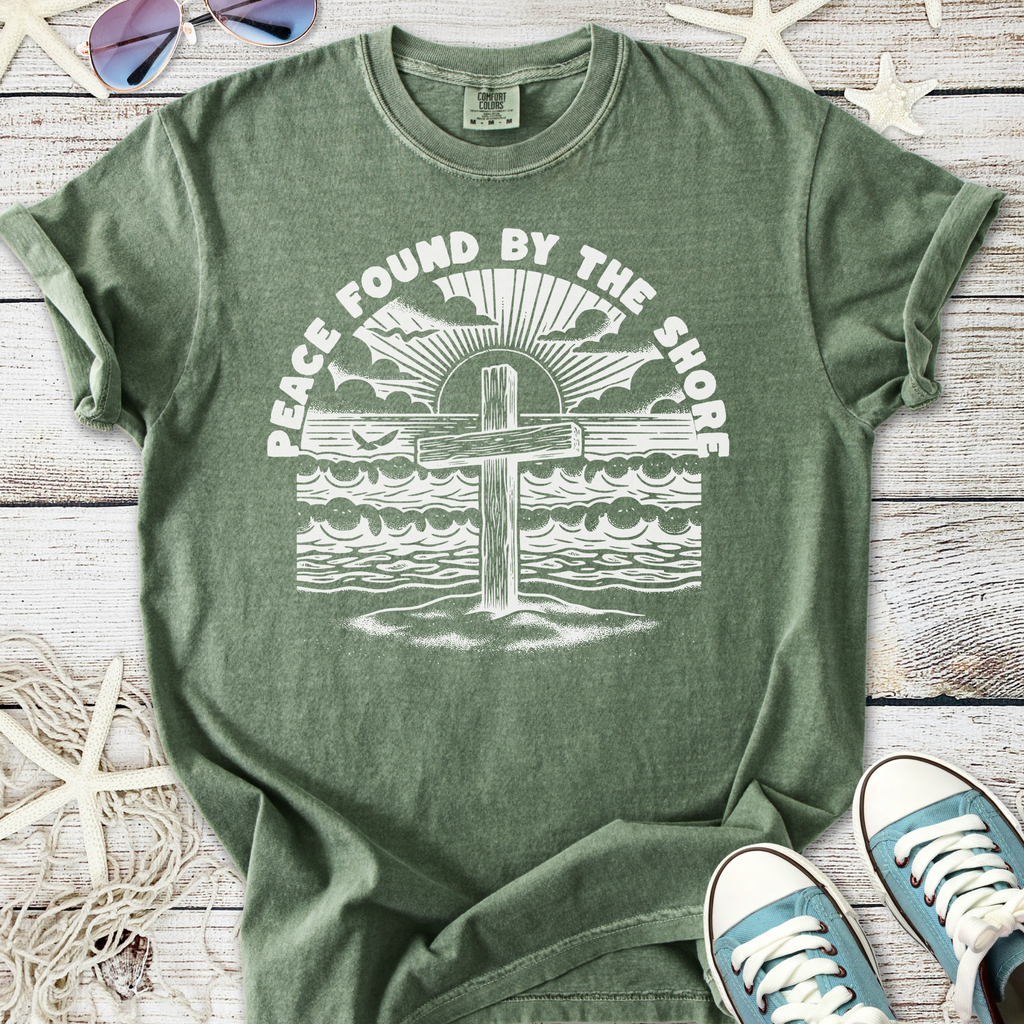 Green unisex t-shirt featuring a beach cross design with the text 'Peace Found By The Shore'.