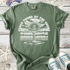 Green unisex t-shirt featuring a beach cross design with the text 'Peace Found By The Shore'.
