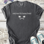 Gray cotton t-shirt with 'retired & beached' palm tree graphic, perfect for beach lovers.