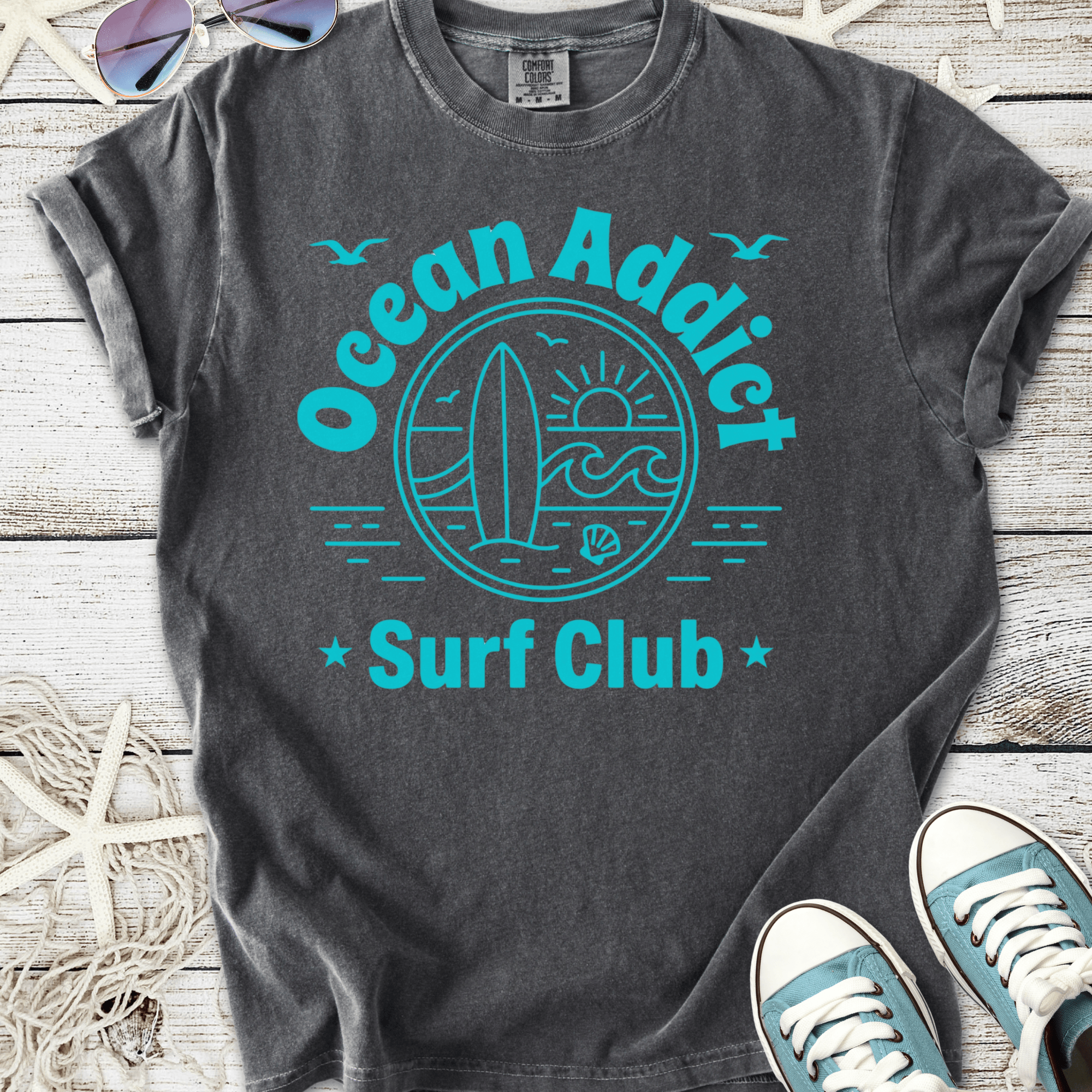 Gray Ocean Addict Surf Club t-shirt with blue graphic design and surfboard illustration.
