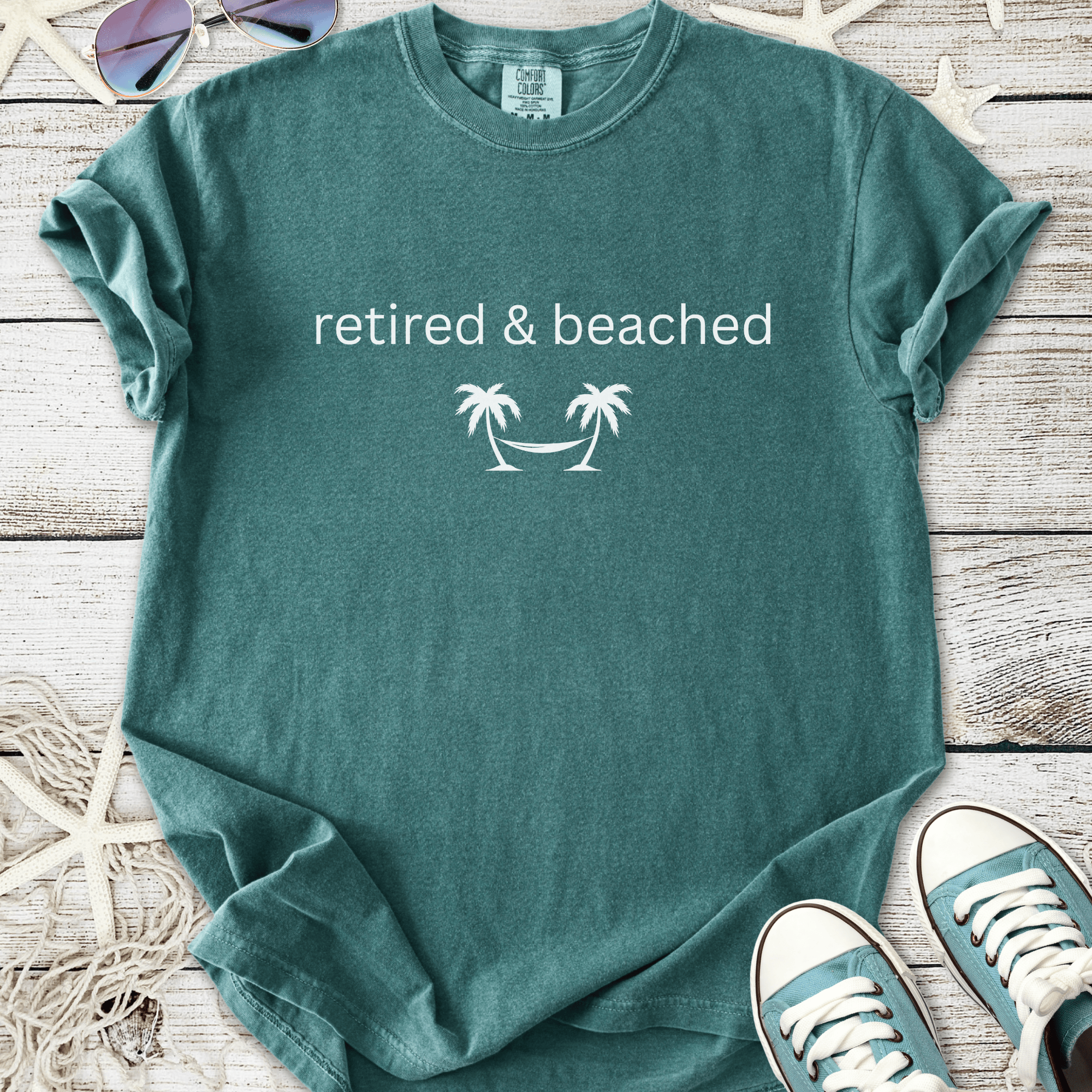 Teal cotton t-shirt featuring 'retired & beached' with palm tree graphic, perfect for beach lovers.