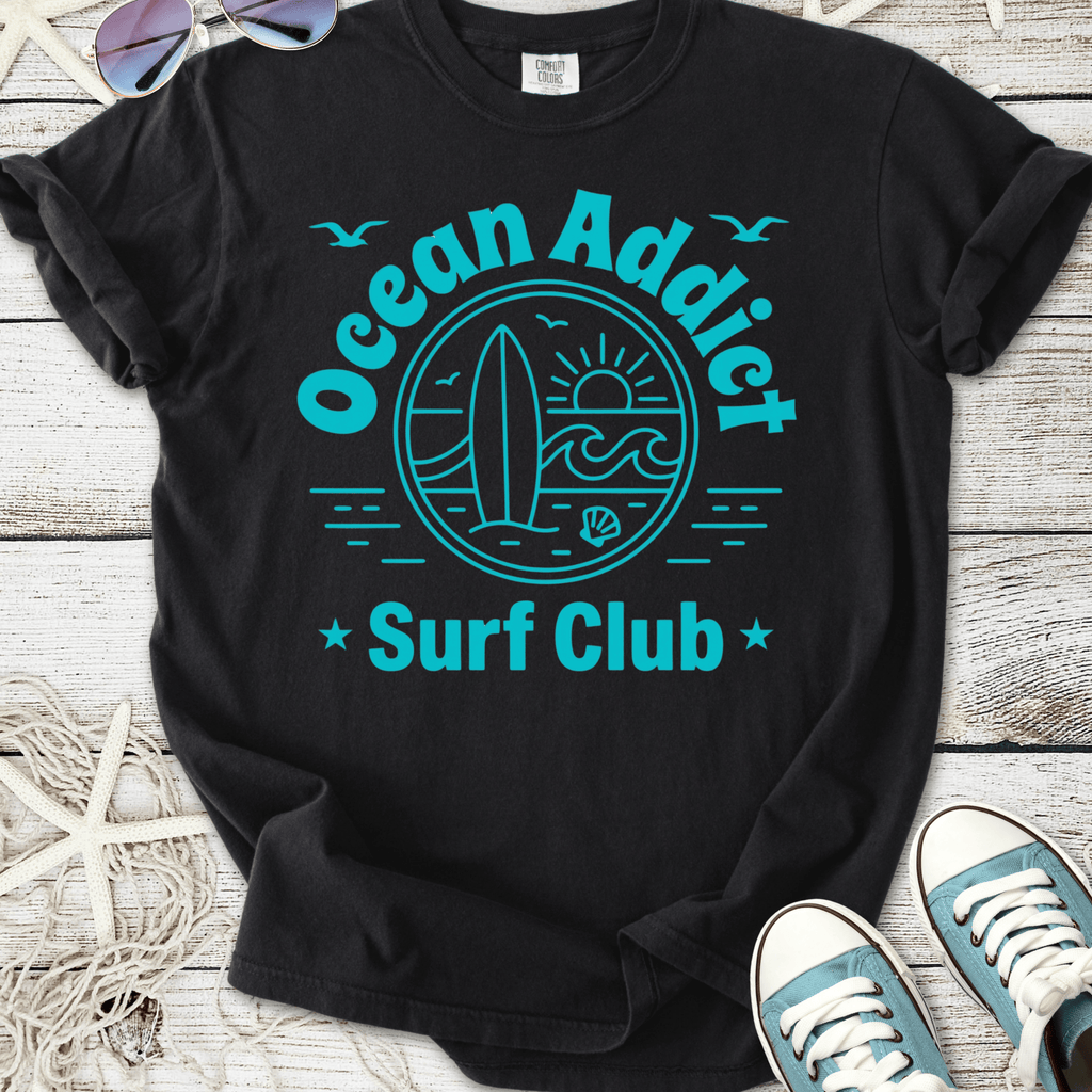 Black cotton t-shirt featuring 'Ocean Addict Surf Club' graphic in teal, perfect for beach lovers.