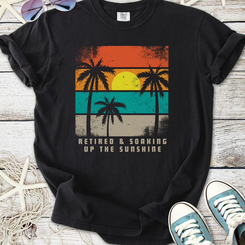 Black t-shirt with retro palm tree design and 'Retired & Soaking Up the Sunshine' text, perfect for vacations.