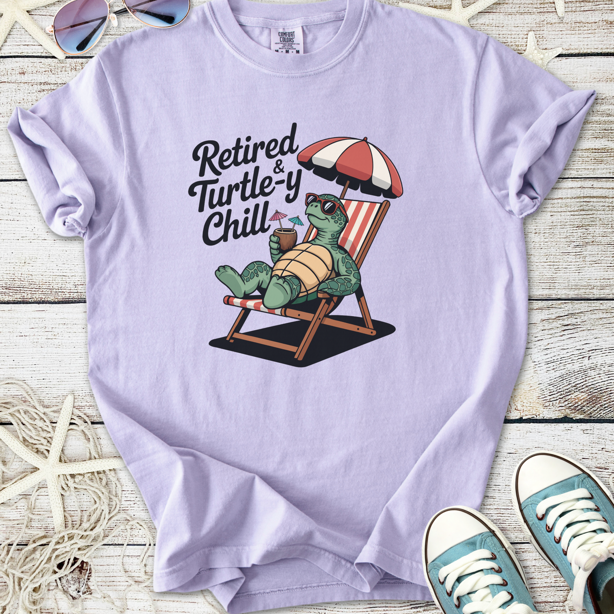 Light purple t-shirt featuring a cartoon turtle relaxing with drinks, text 'Retired & Turtle-y Chill'.