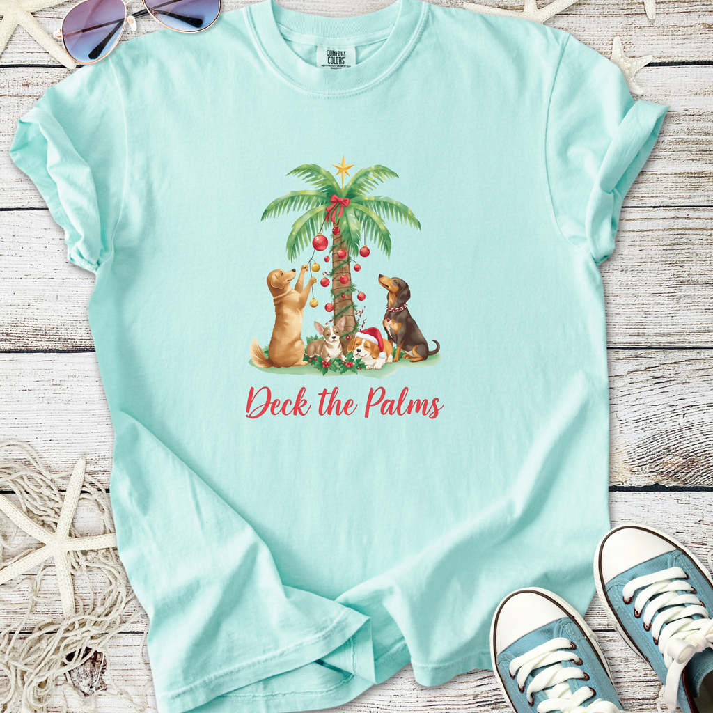 Teal t-shirt featuring playful dogs decorating a palm tree for Christmas, ideal for pet lovers.