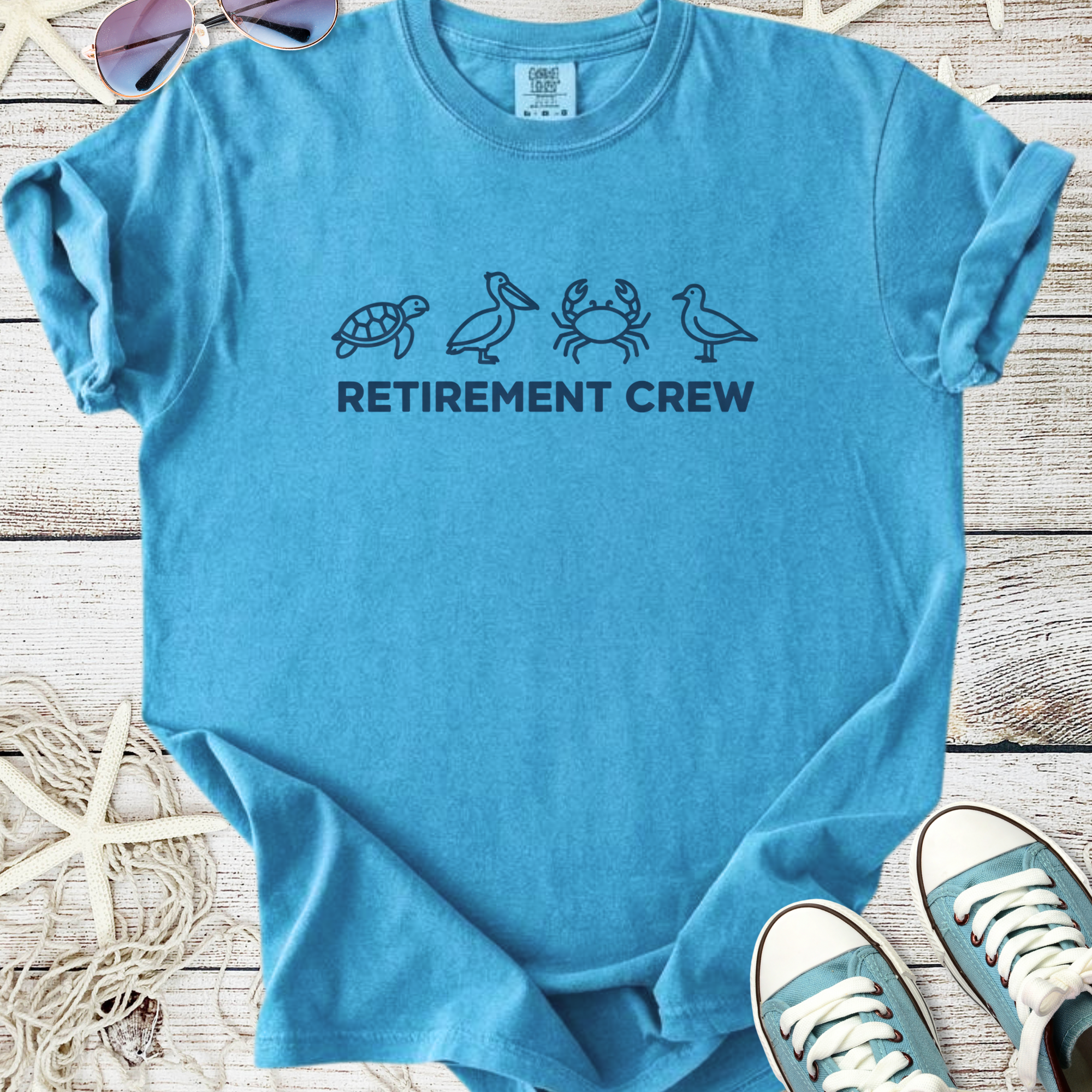Light blue retirement crew t-shirt featuring turtle, pelican, crab, and bird graphics.