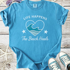 Blue cotton t-shirt with "Life Happens The Beach Heals" graphic, featuring waves and starfish design.