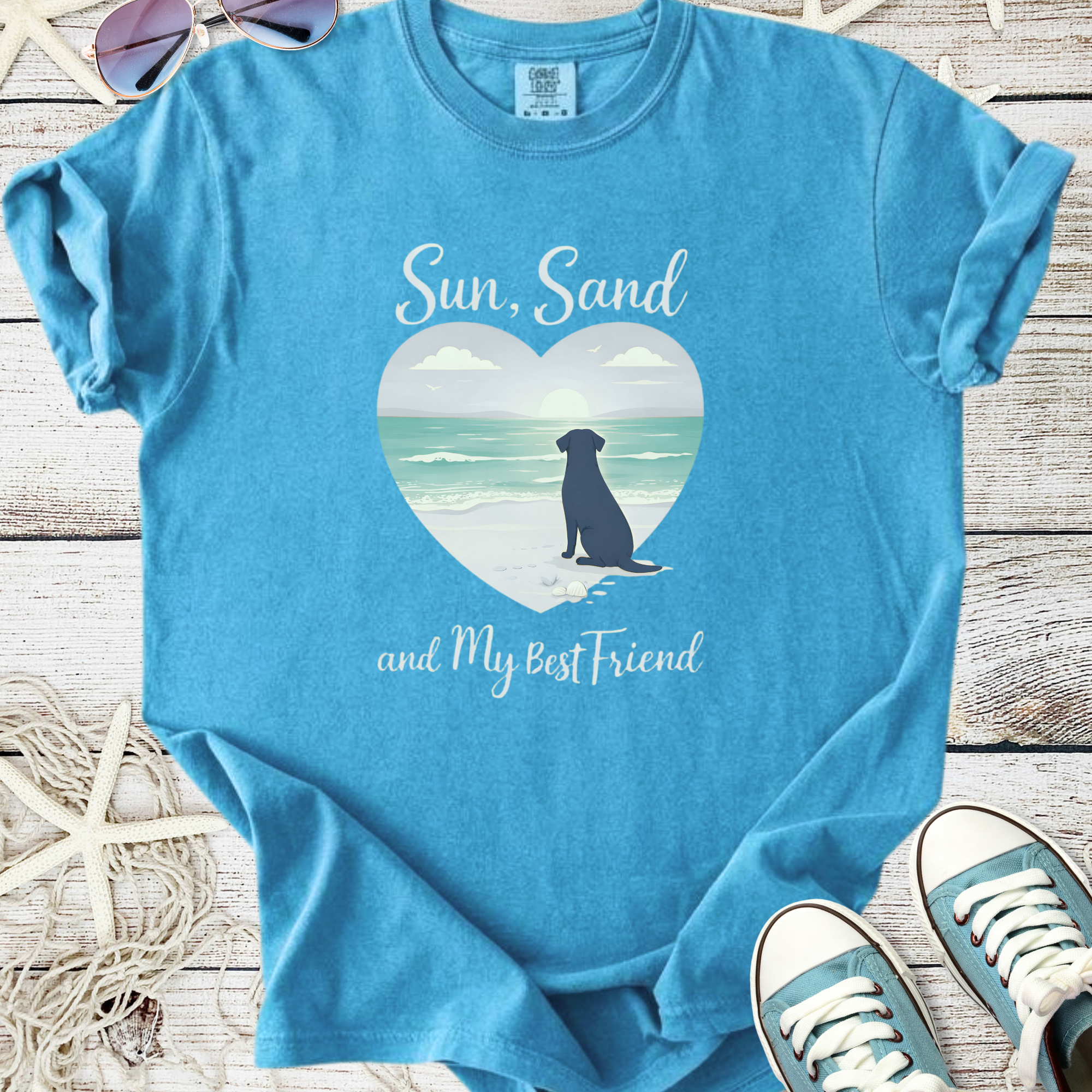 Light blue graphic tee featuring a dog silhouette and beach scene with the text 'Sun, Sand, and My Best Friend'.