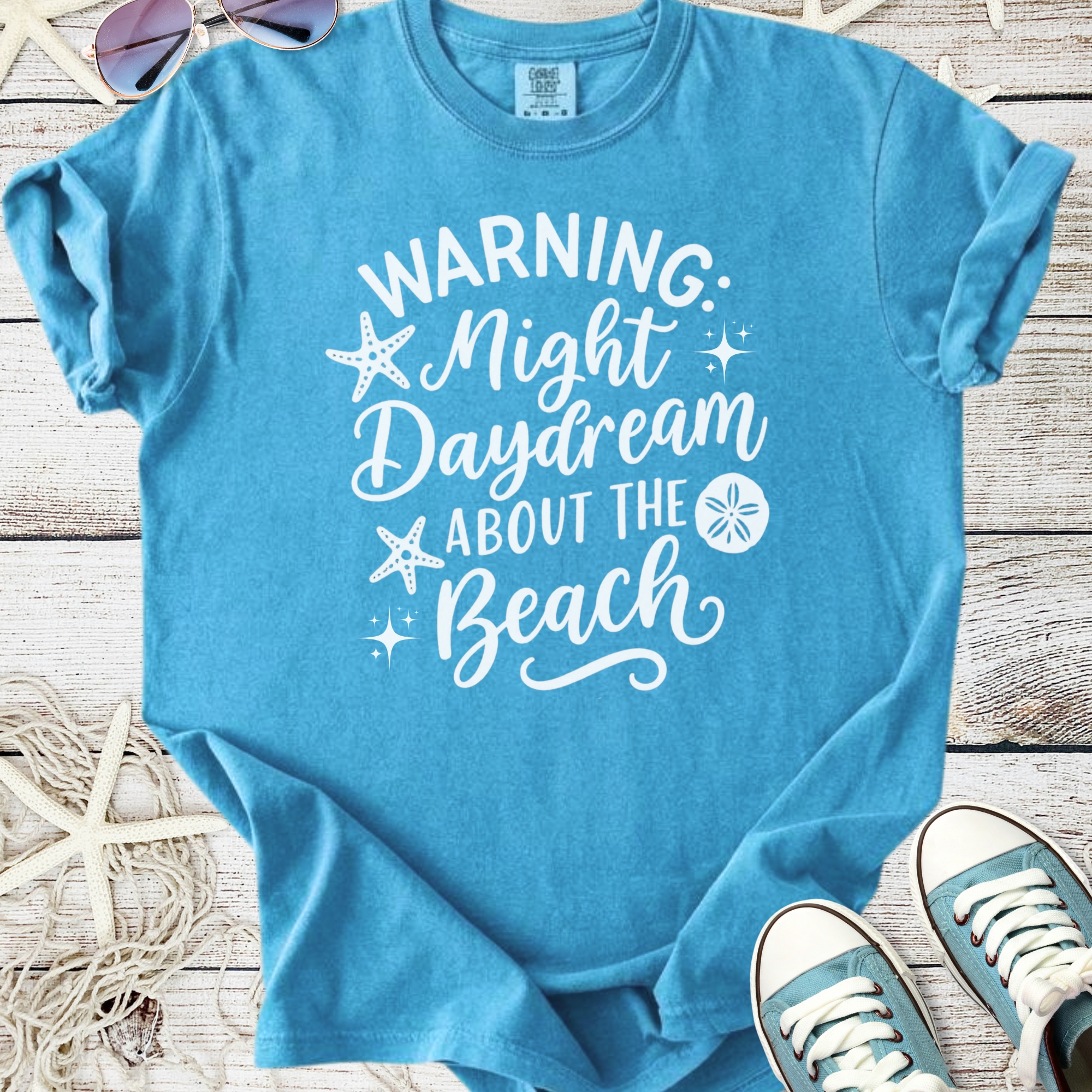 Blue cotton t-shirt with 'Warning: Night Daydream About the Beach' print, perfect for beach lovers.