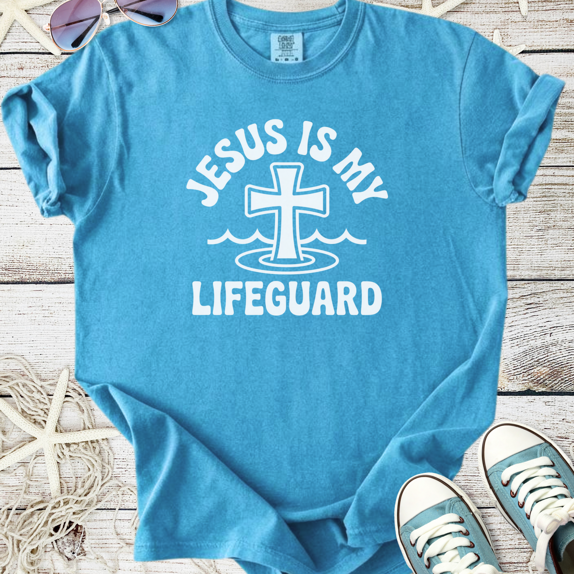 Light blue t-shirt featuring 'Jesus is My Lifeguard' graphic and cross design, perfect for summer wear.