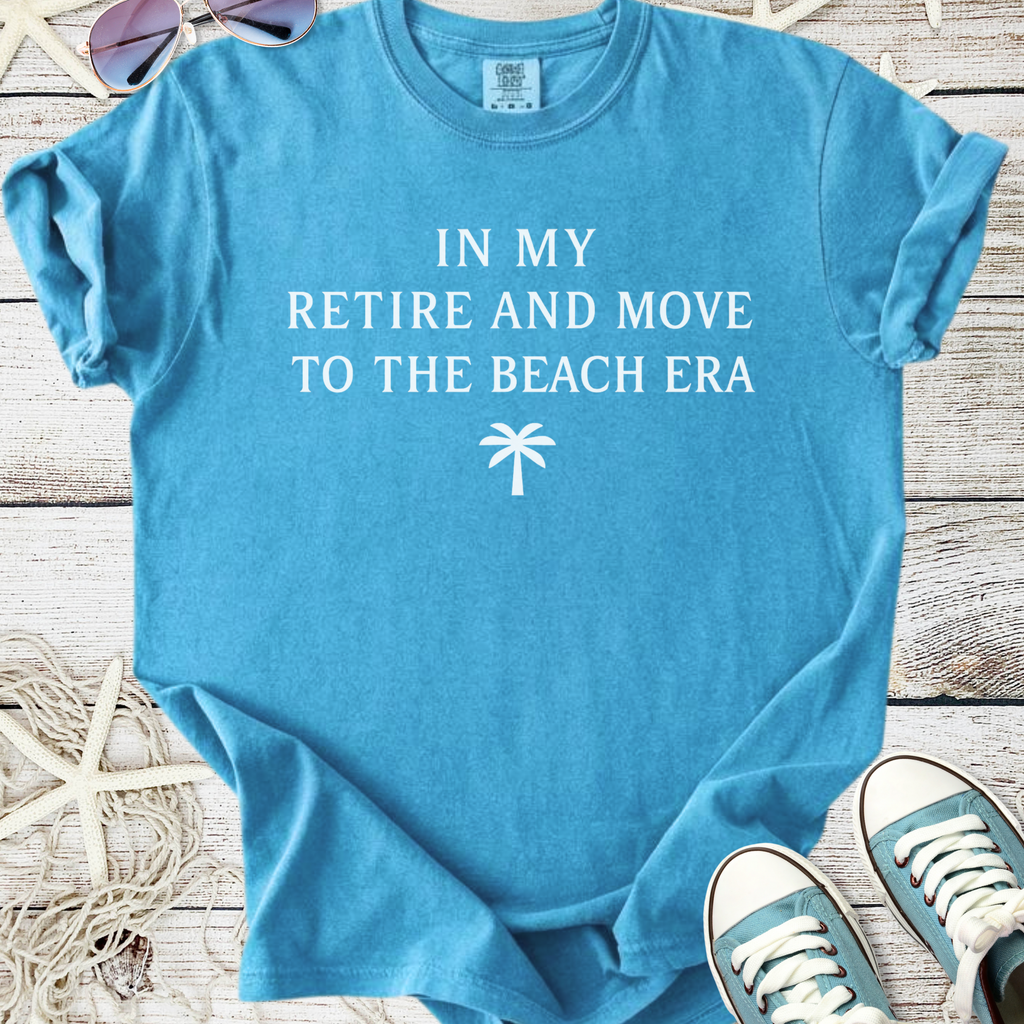 Light blue cotton t-shirt with 'In My Retire and Move to the Beach Era' printed design.