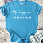 Light blue t-shirt with "life happens THE BEACH HELPS" printed, perfect for beach lovers and summer wear.