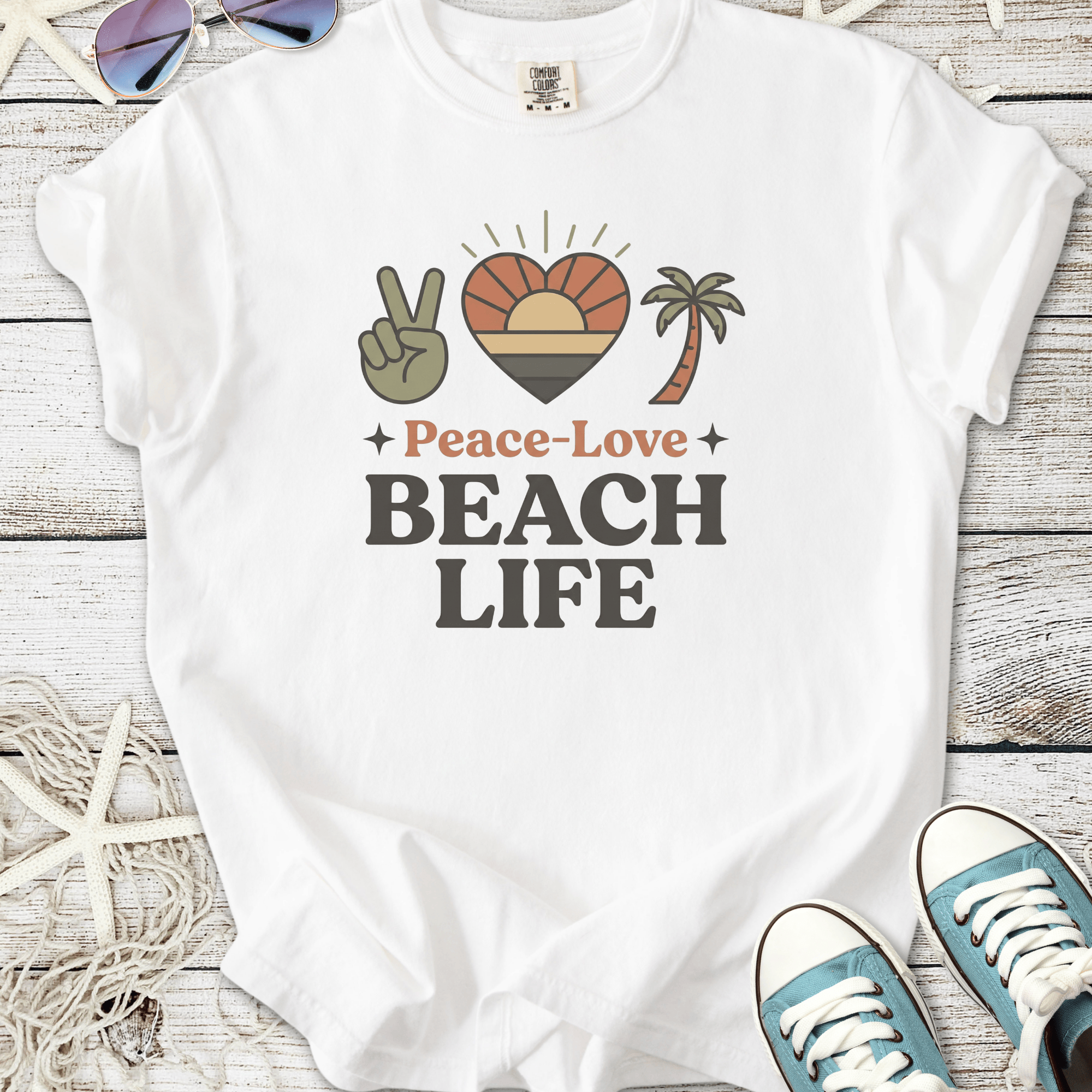 White t-shirt featuring 'Peace-Love Beach Life' graphic with palm tree and sunset design.