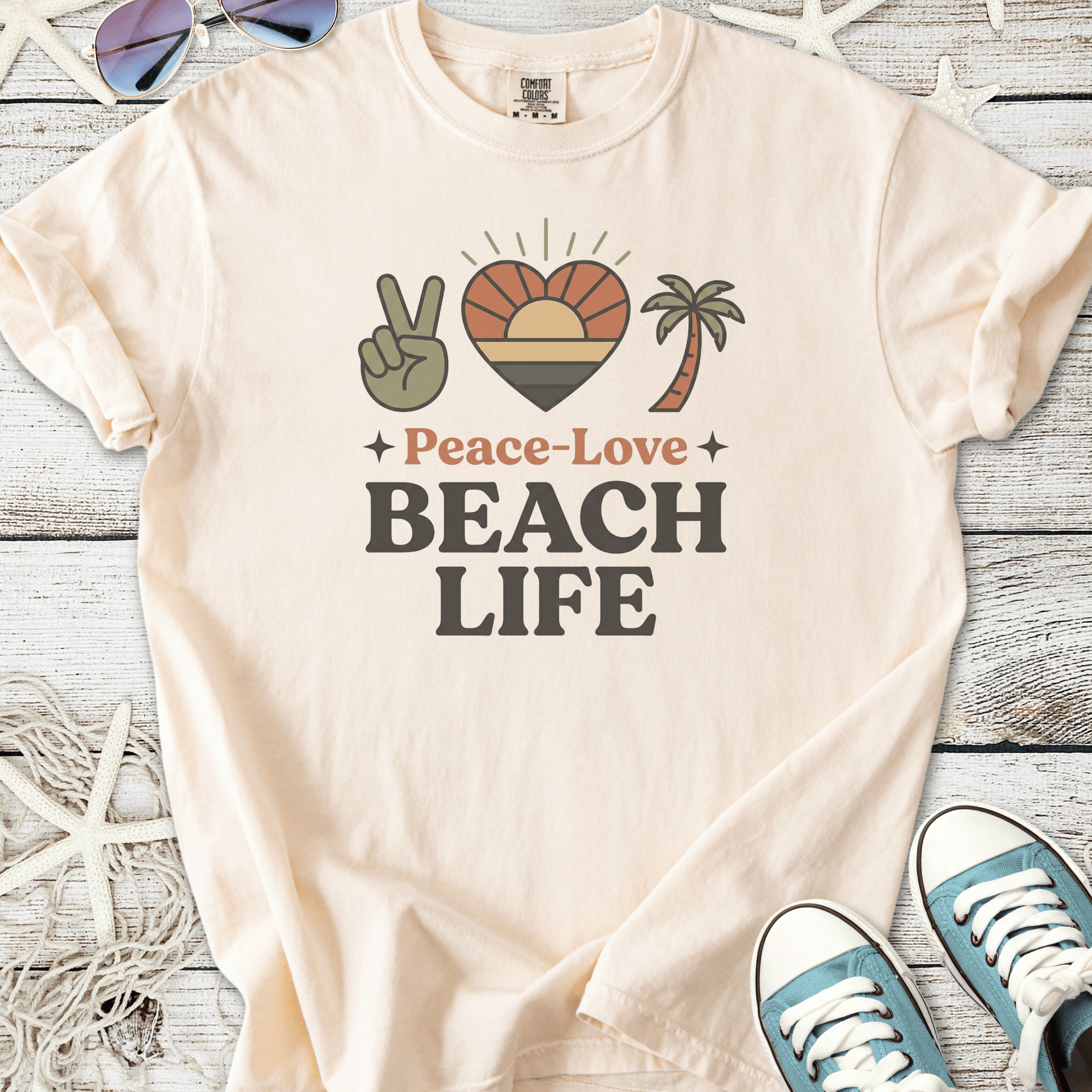 Cream cotton t-shirt with 'Peace-Love Beach Life' graphic, featuring palm tree and sunset design.