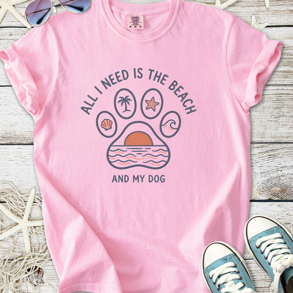 Pink graphic tee with beach-themed design, featuring a paw print and text, 'All I Need is the Beach and My Dog'.