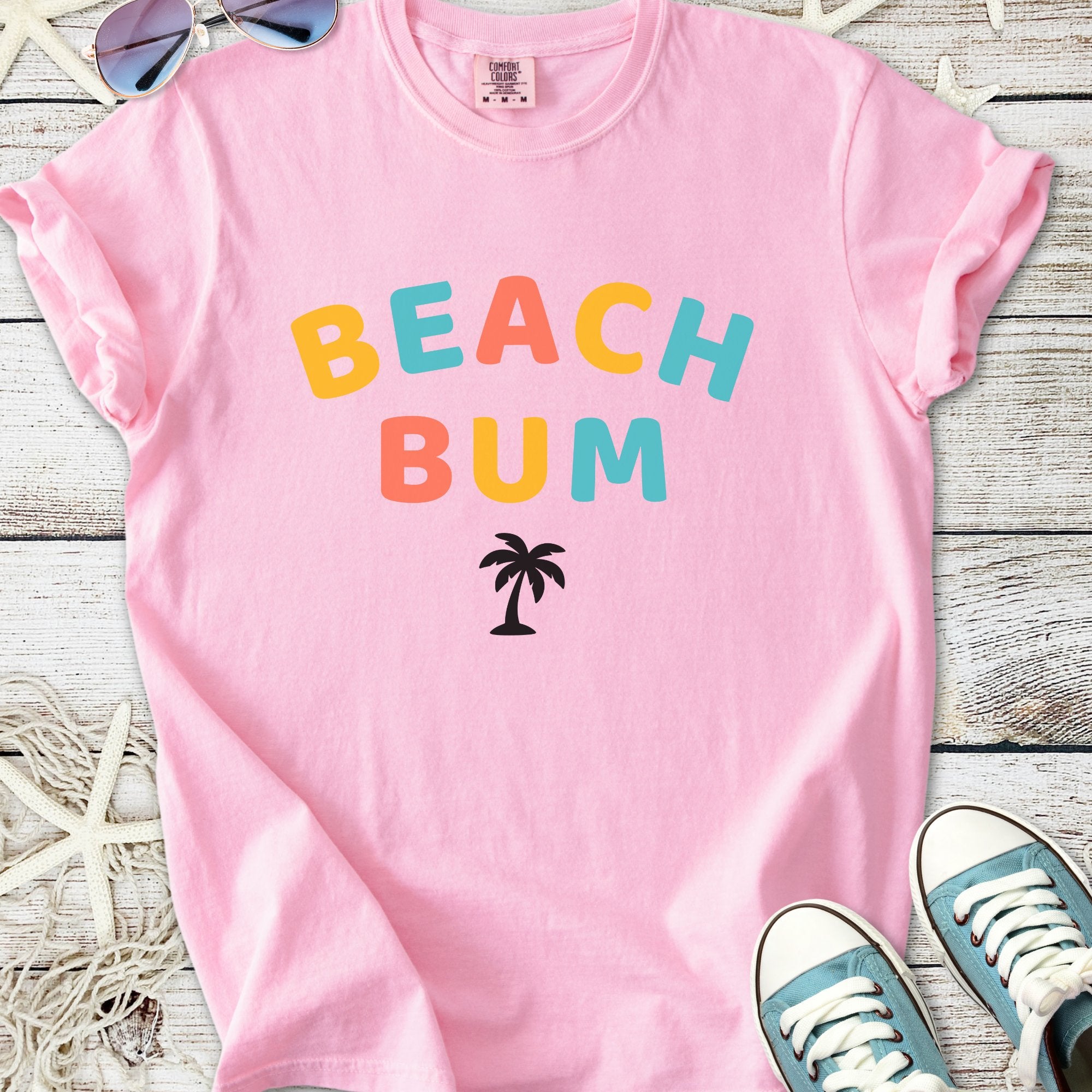 Pink cotton t-shirt with 'BEACH BUM' graphic and palm tree design, perfect for summer outings.