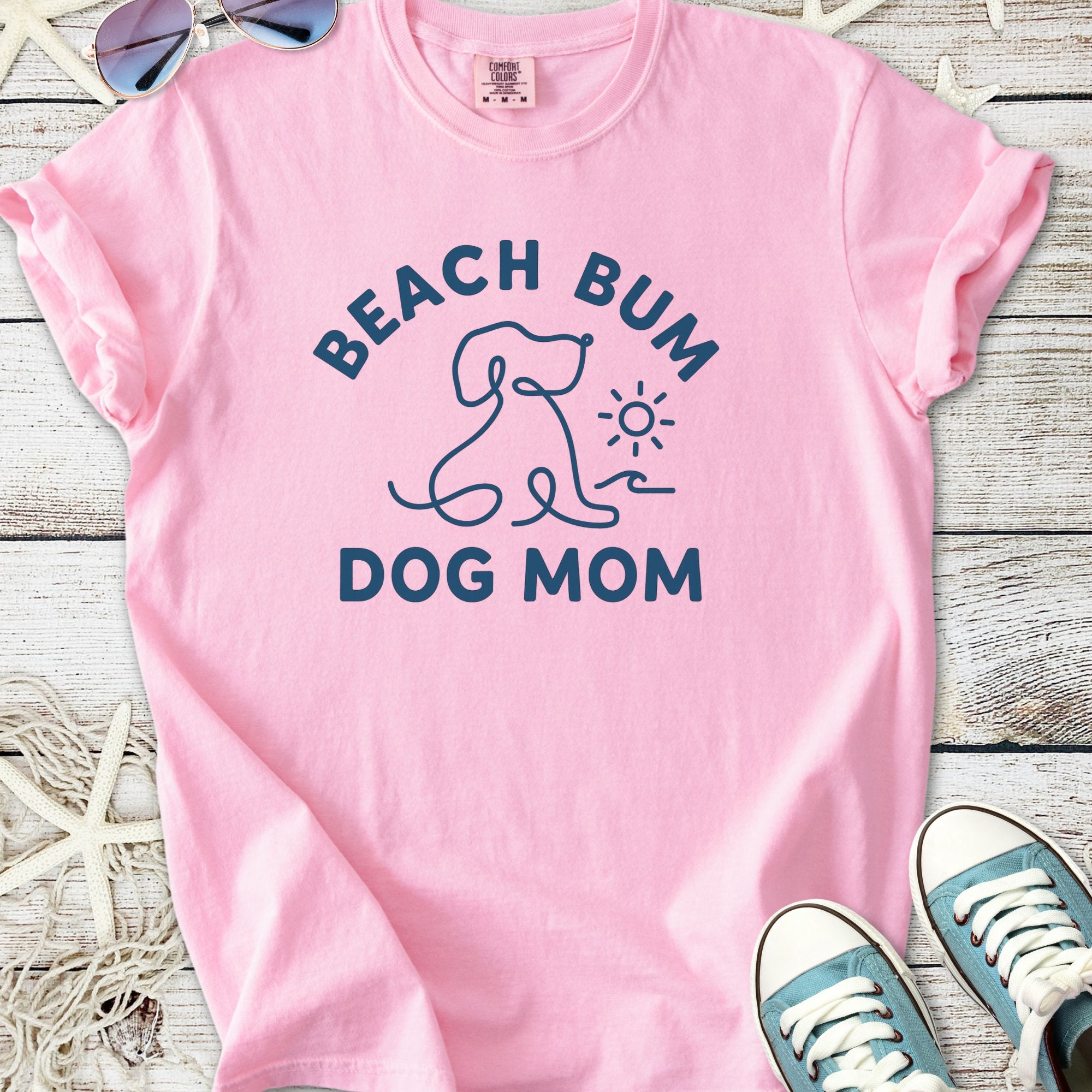 Pink graphic tee featuring 'Beach Bum Dog Mom' with dog and sun design, perfect for dog lovers.