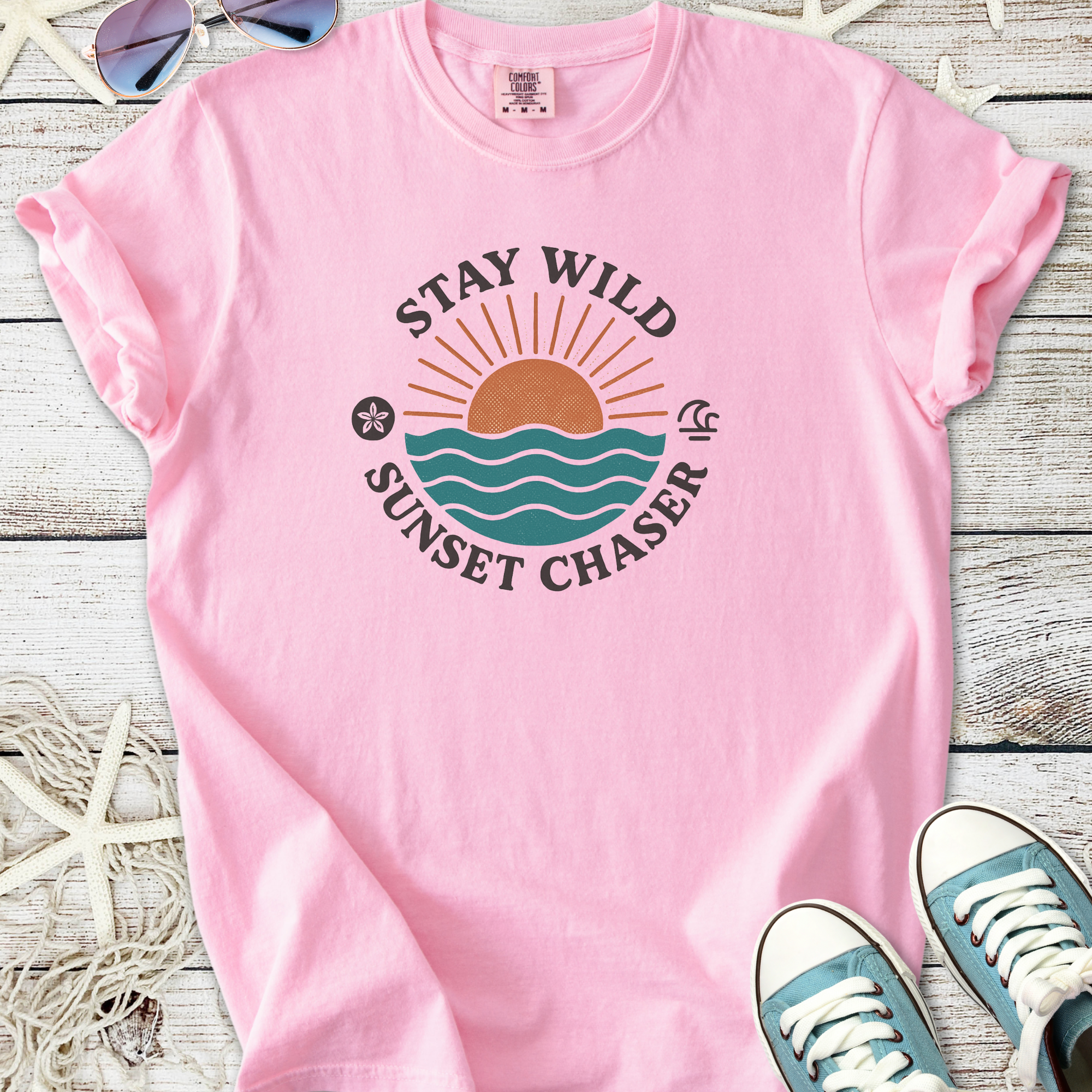 Pink 'Stay Wild Sunset Chaser' graphic t-shirt made of soft cotton, perfect for beach lovers.
