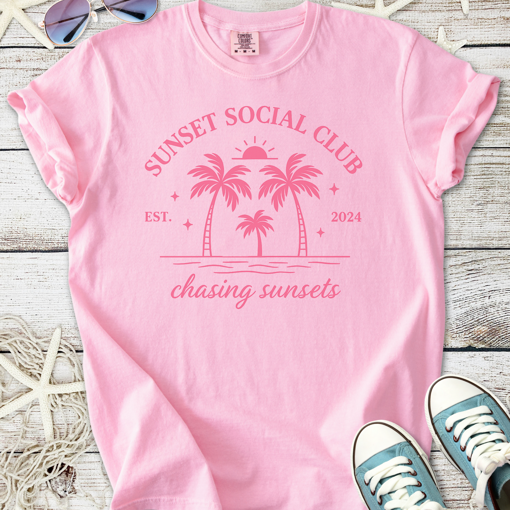 Pink cotton t-shirt with 'Sunset Social Club' graphic, featuring palm trees and beach motif, perfect for summer.