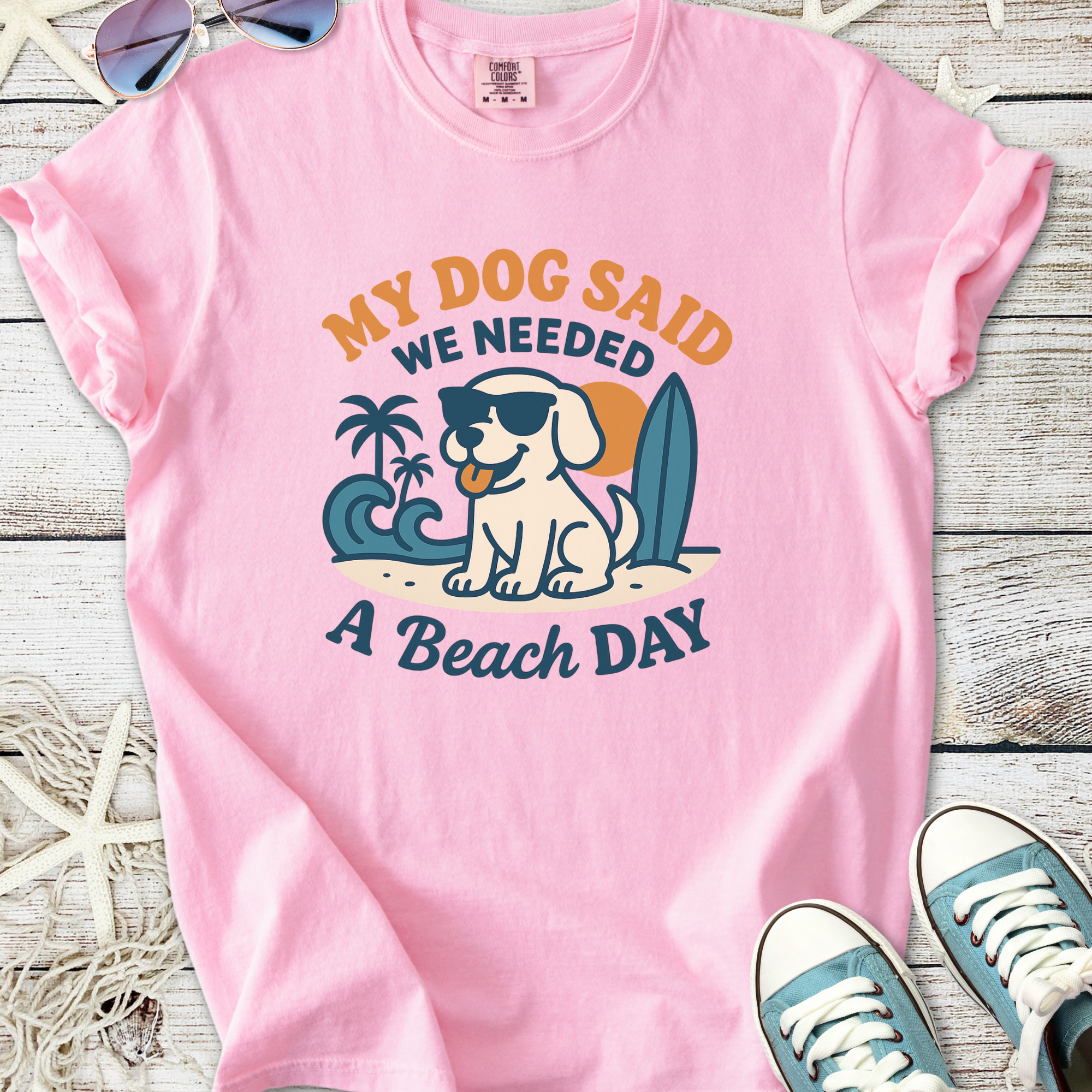 Pink graphic t-shirt featuring a dog in sunglasses with the phrase 'My Dog Said We Needed A Beach Day'.