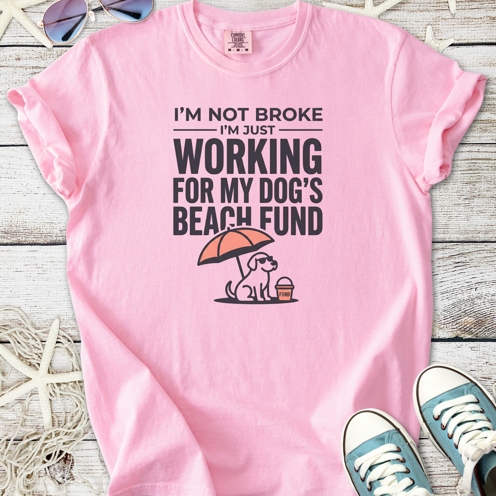 Pink graphic t-shirt with humorous text about working for dog's beach fund, casual style.