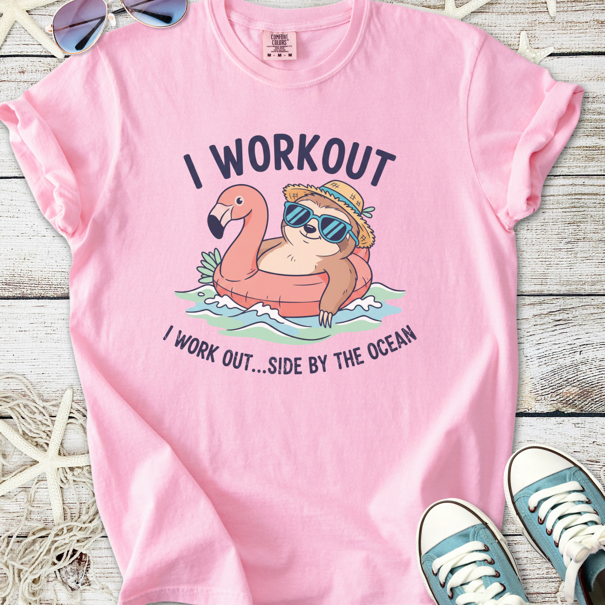 Pink t-shirt featuring a cartoon sloth on a flamingo float, text 'I WORKOUT...SIDE BY THE OCEAN'.