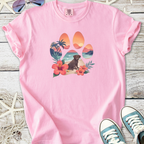 Pink cotton t-shirt with a colorful paw print design featuring a dog, flowers, and a beach scene.