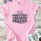 Pink t-shirt with 'Pawsitively Beach Obsessed' graphic, perfect for dog lovers and beachgoers.