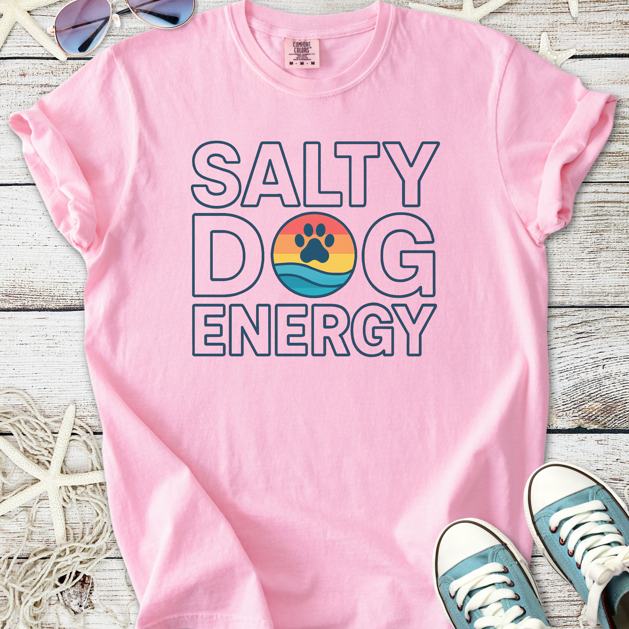 Pink cotton t-shirt featuring 'Salty Dog Energy' graphic with paw print and beach colors.