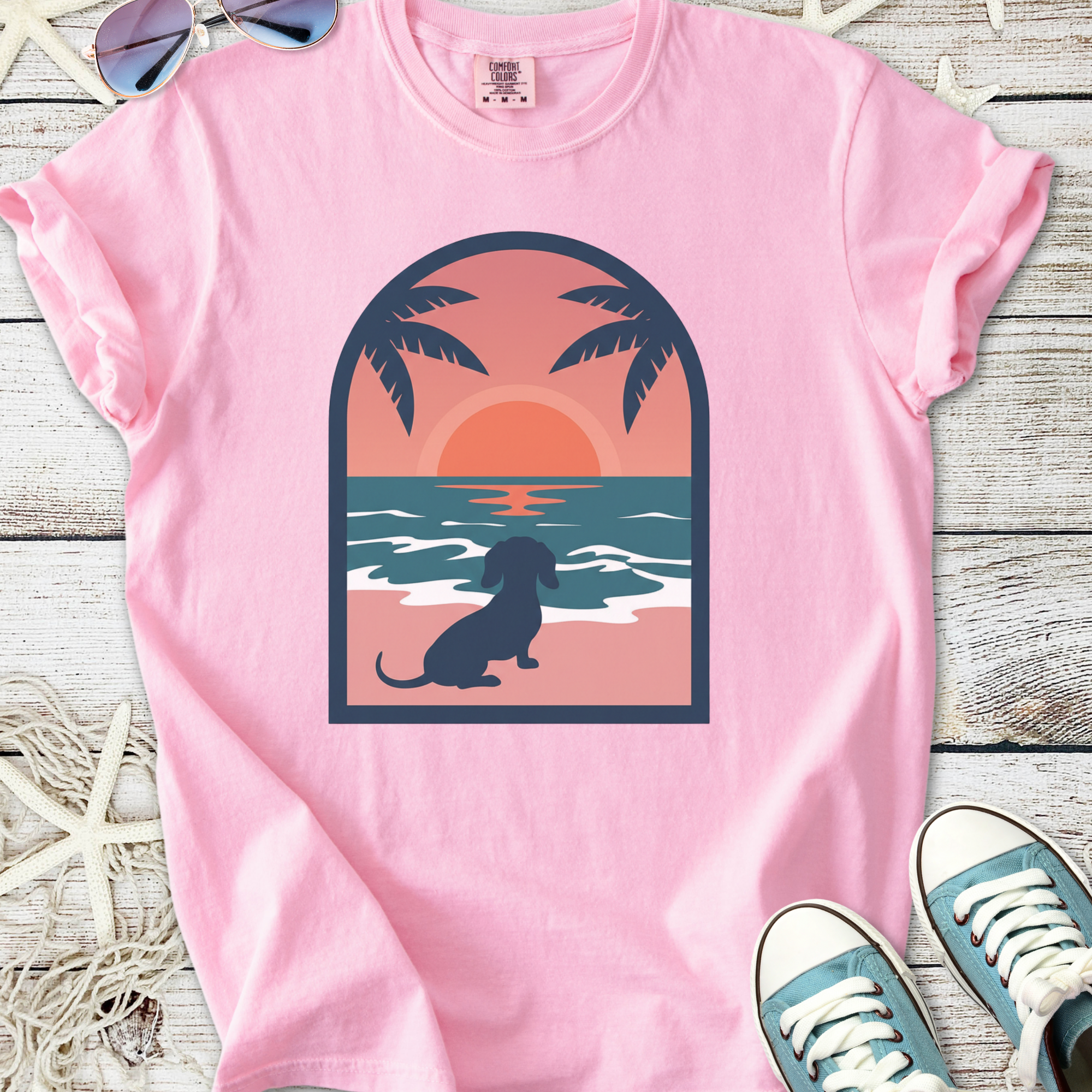 Pink graphic t-shirt with a sunset and dog design, perfect for casual summer wear.