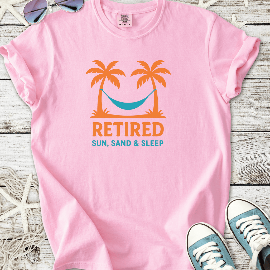 Pink cotton t-shirt with 'Retired, Sun, Sand & Sleep' graphic featuring palm trees and a hammock.