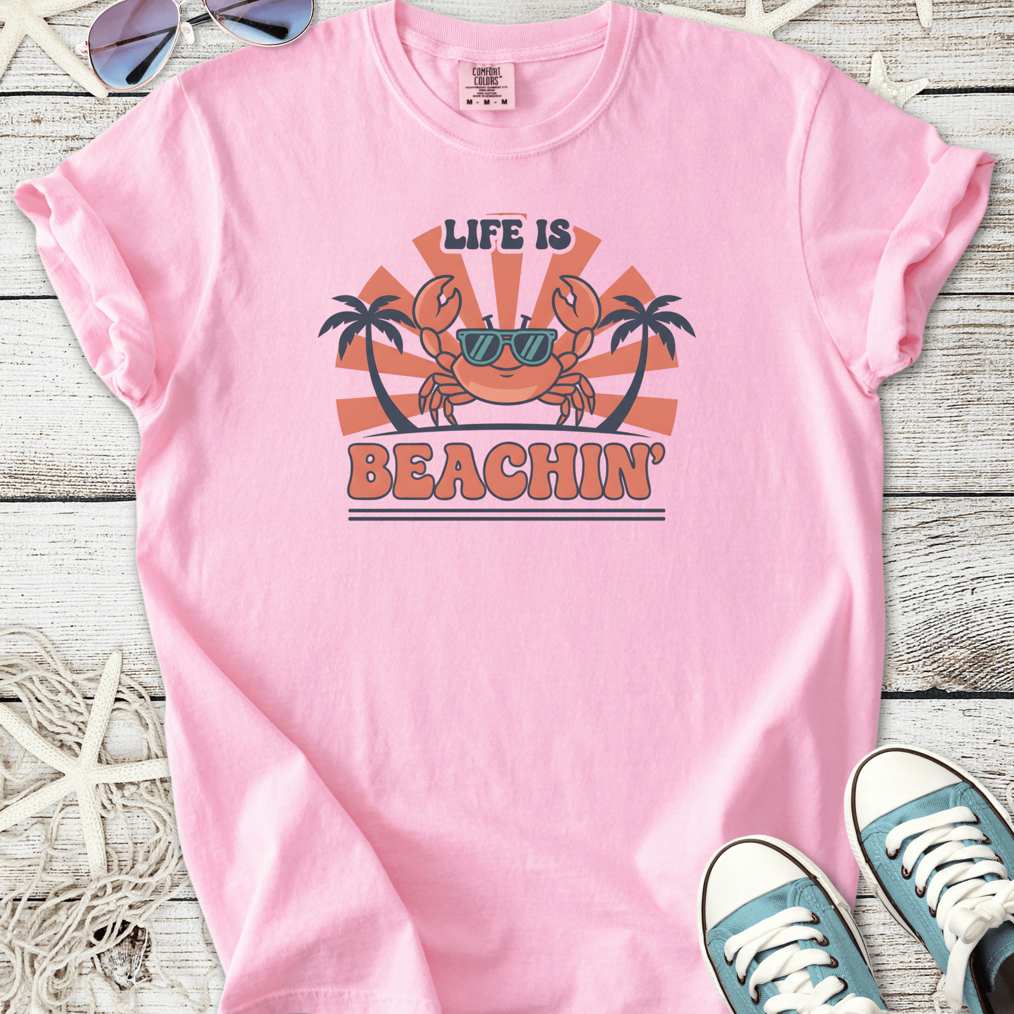 Pink graphic tee featuring a playful crab design with 'Life is Beachin'' text and palm trees.