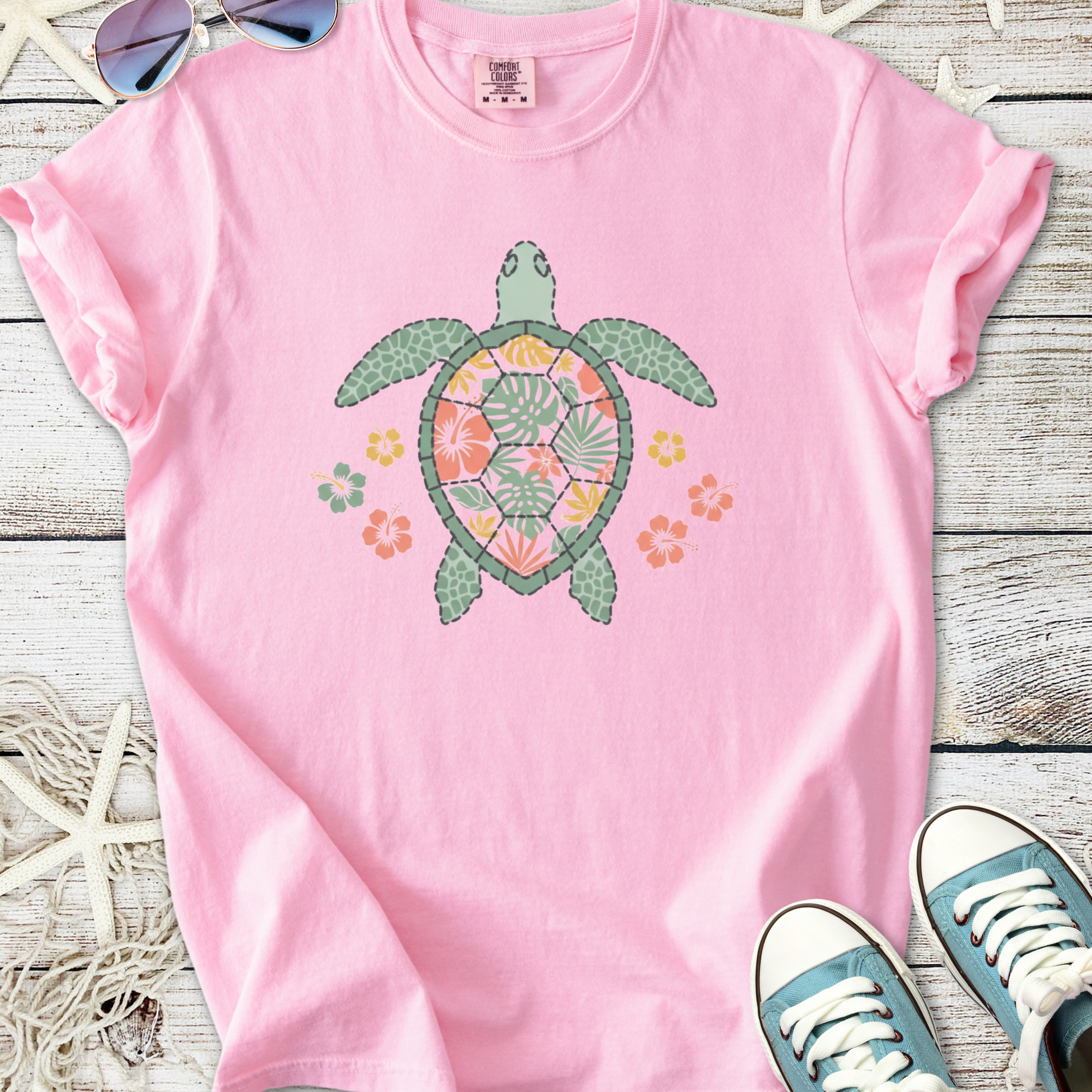 Pink cotton t-shirt featuring a colorful turtle design with floral elements, perfect for casual beachwear.
