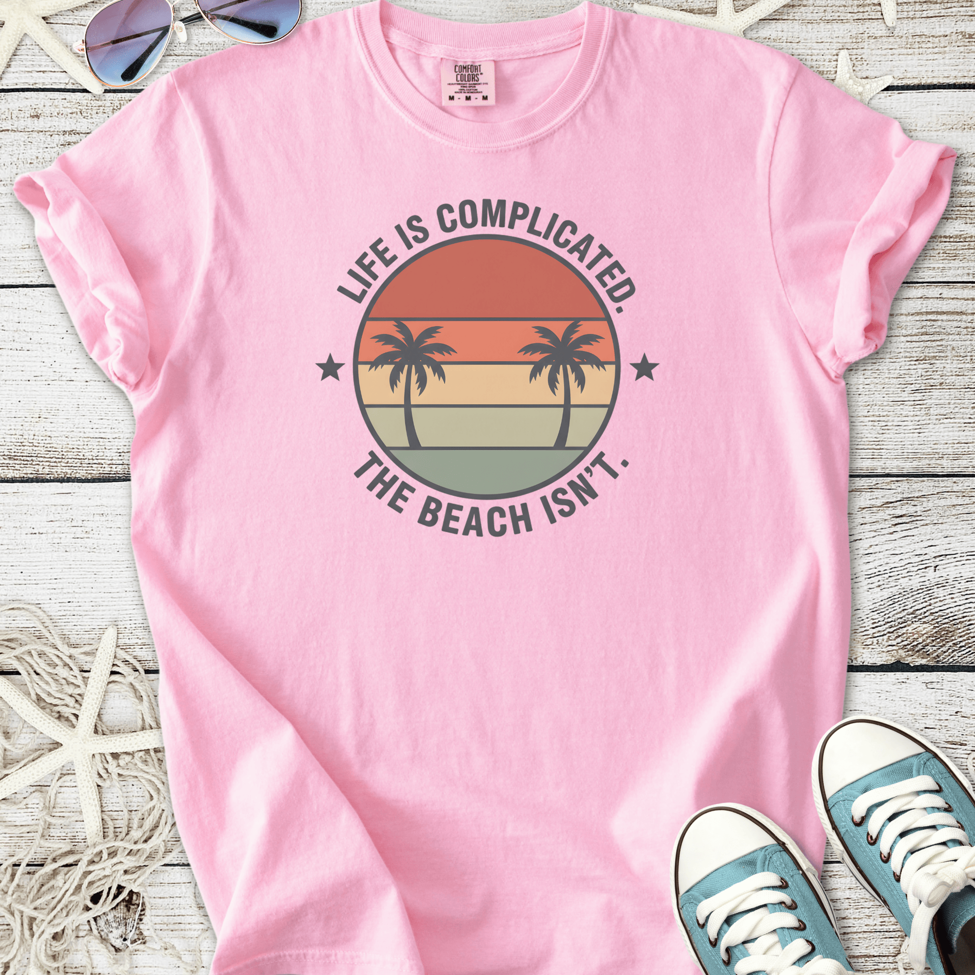 Pink cotton t-shirt with beach-themed graphic and palm trees, perfect for casual summer wear.