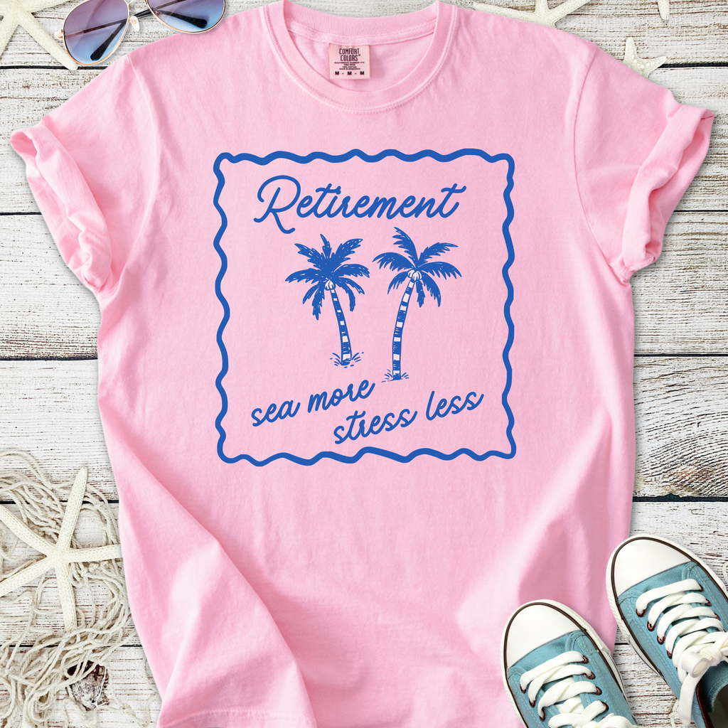 Pink graphic t-shirt featuring palm tree design and 'Retirement: sea more, stress less' text.