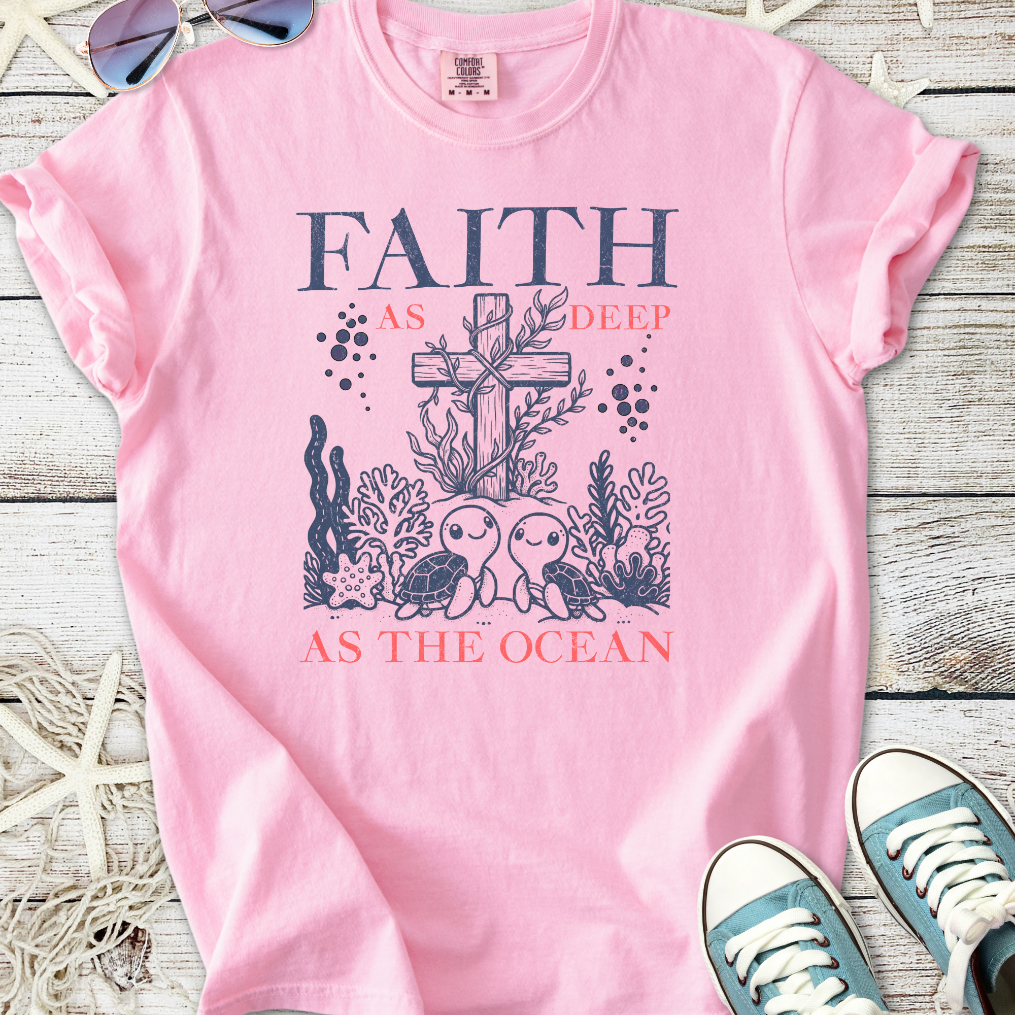 Cute pink t-shirt with ocean-themed design, featuring turtles and a cross, promoting faith.