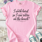 Pink t-shirt with the quote 'I work hard so I can retire on the beach', cotton material, casual style.
