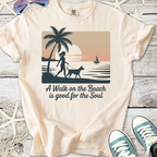 Cream graphic tee with beach scene, palm tree, woman walking dog, and text about soul benefits of beach walks.