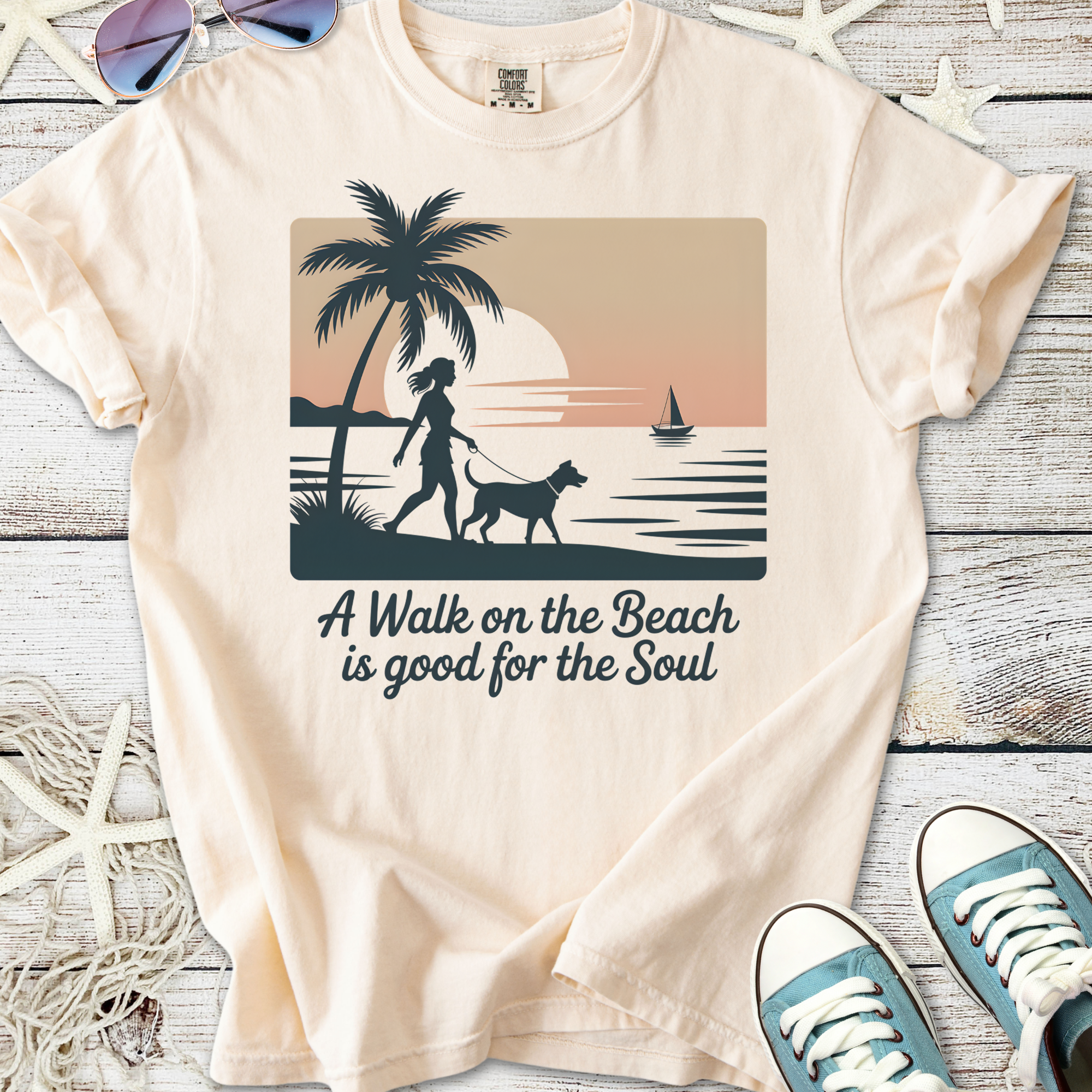 Cream graphic tee with beach scene, palm tree, woman walking dog, and text about soul benefits of beach walks.