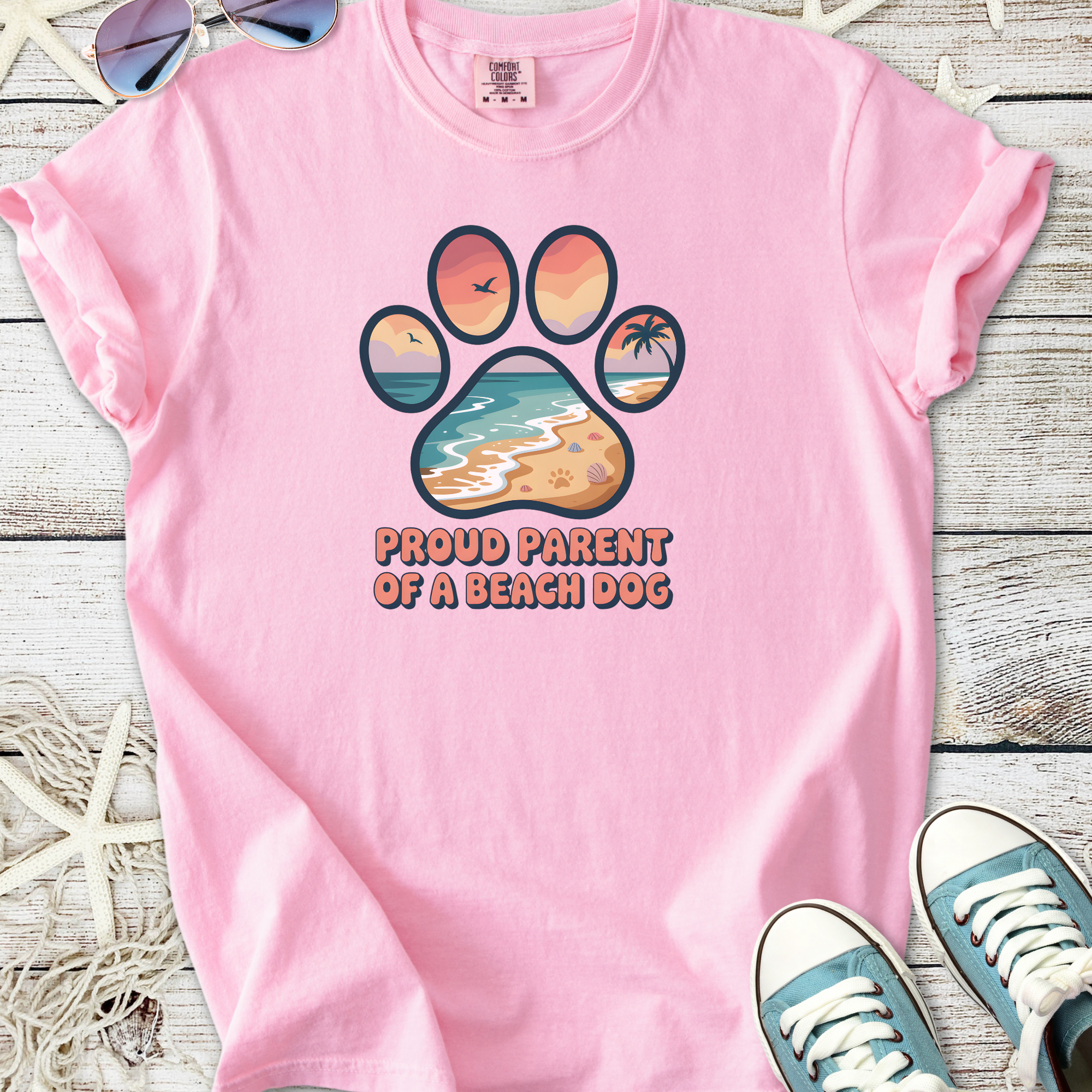 Pink t-shirt featuring 'Proud Parent of a Beach Dog' graphic with a beach-themed paw print design.