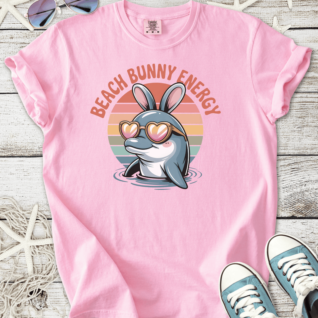 Pink t-shirt featuring a cute dolphin with bunny ears and heart-shaped sunglasses, ideal for beach lovers.