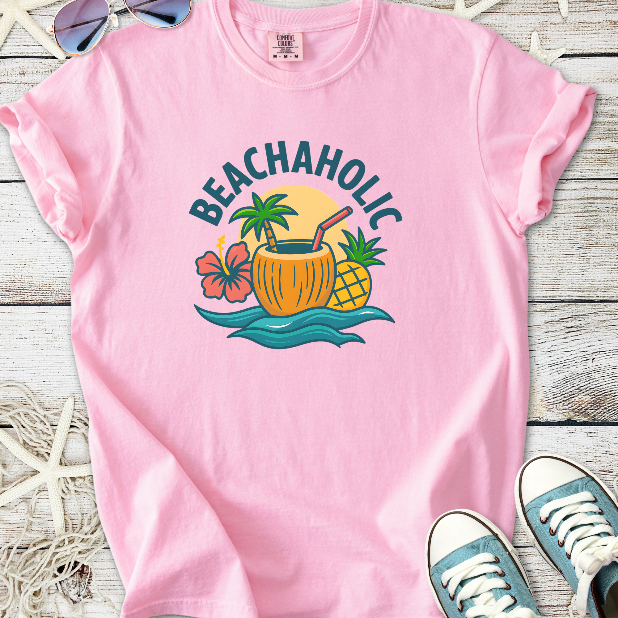 Pink 'Beachaholic' graphic t-shirt featuring tropical design with palm trees and fruits.