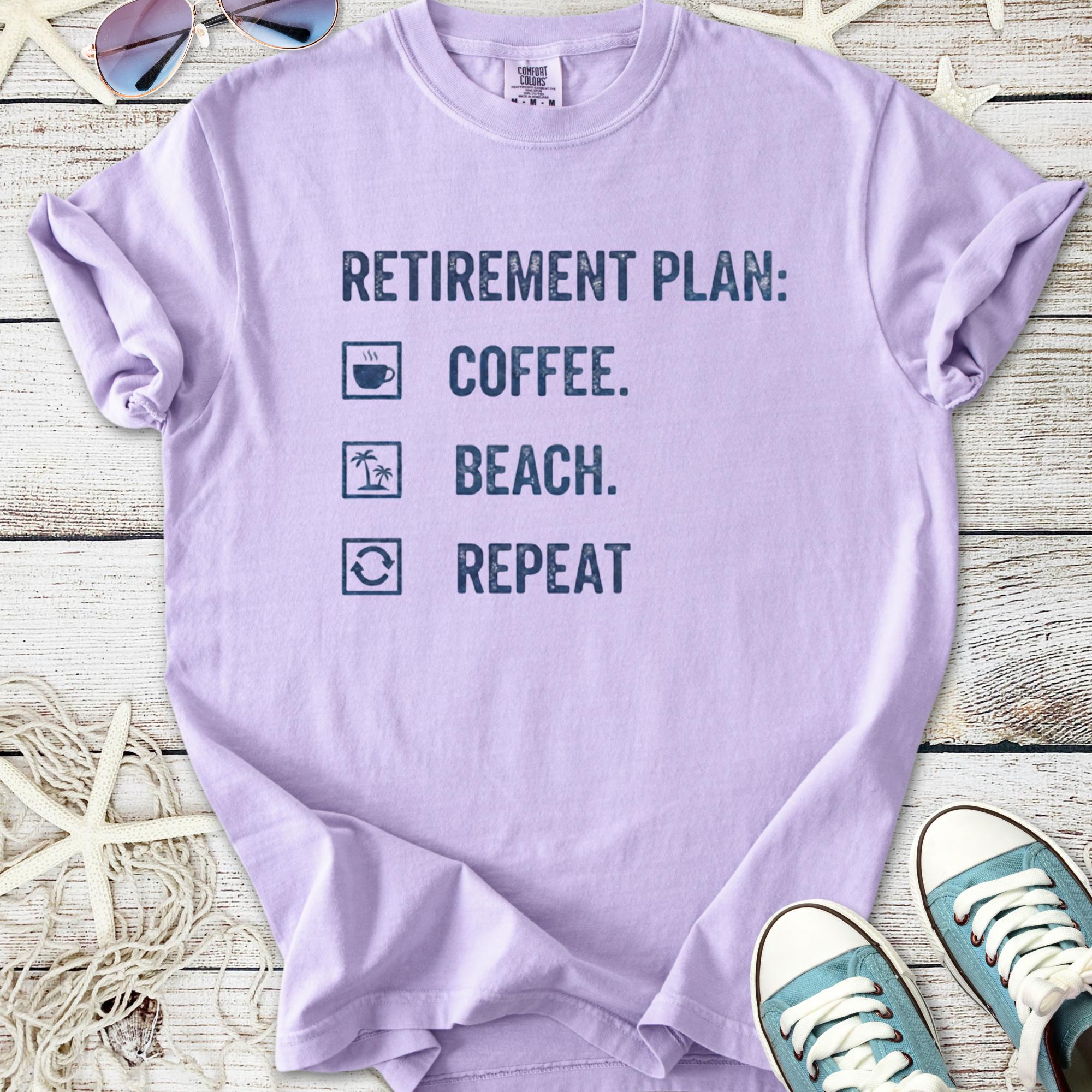 Light purple retirement plan t-shirt featuring coffee, beach, and repeat graphics on soft cotton material.