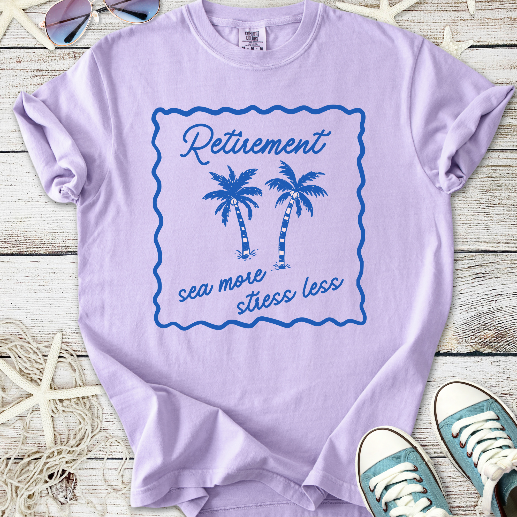Light purple t-shirt with palm tree design and 'Retirement sea more stress less' print.