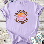 Light purple t-shirt with 'Fetching Sunsets' graphic, featuring a palm tree and sunset design.