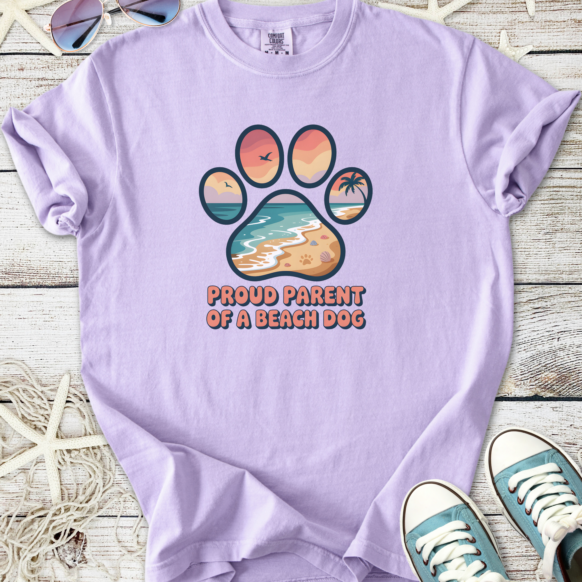 Lavender t-shirt featuring 'Proud Parent of a Beach Dog' graphic with a beach scene and paw print.